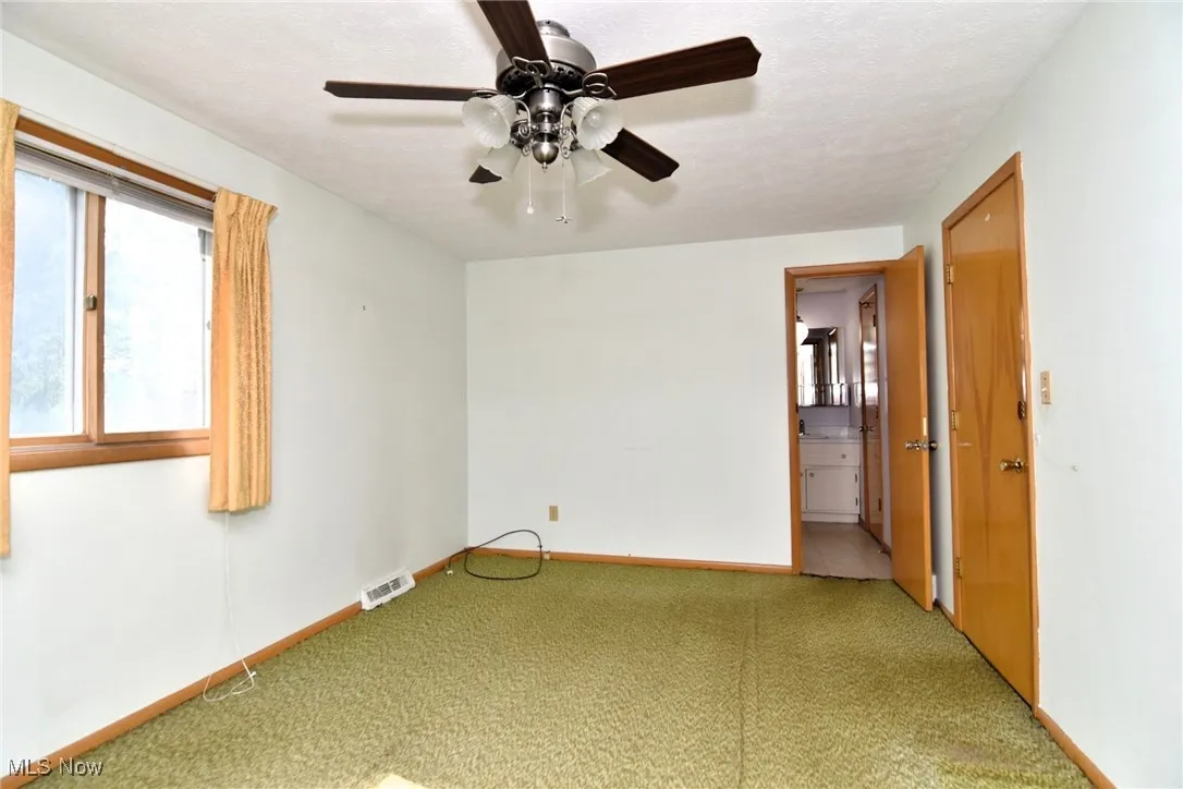 Empty room featuring carpet, baseboards, and ceiling fan