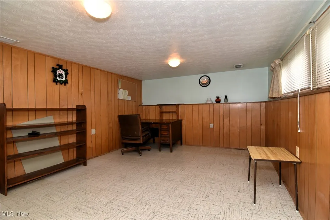 Office area featuring a textured ceiling and wood walls