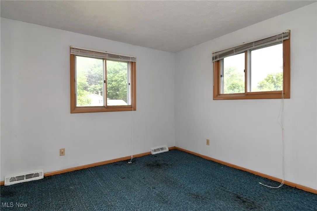Carpeted empty room with baseboards and a textured ceiling