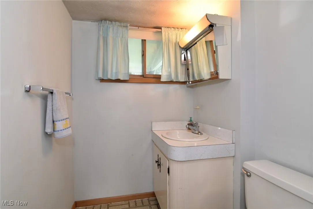 Bathroom with toilet, vanity, and baseboards