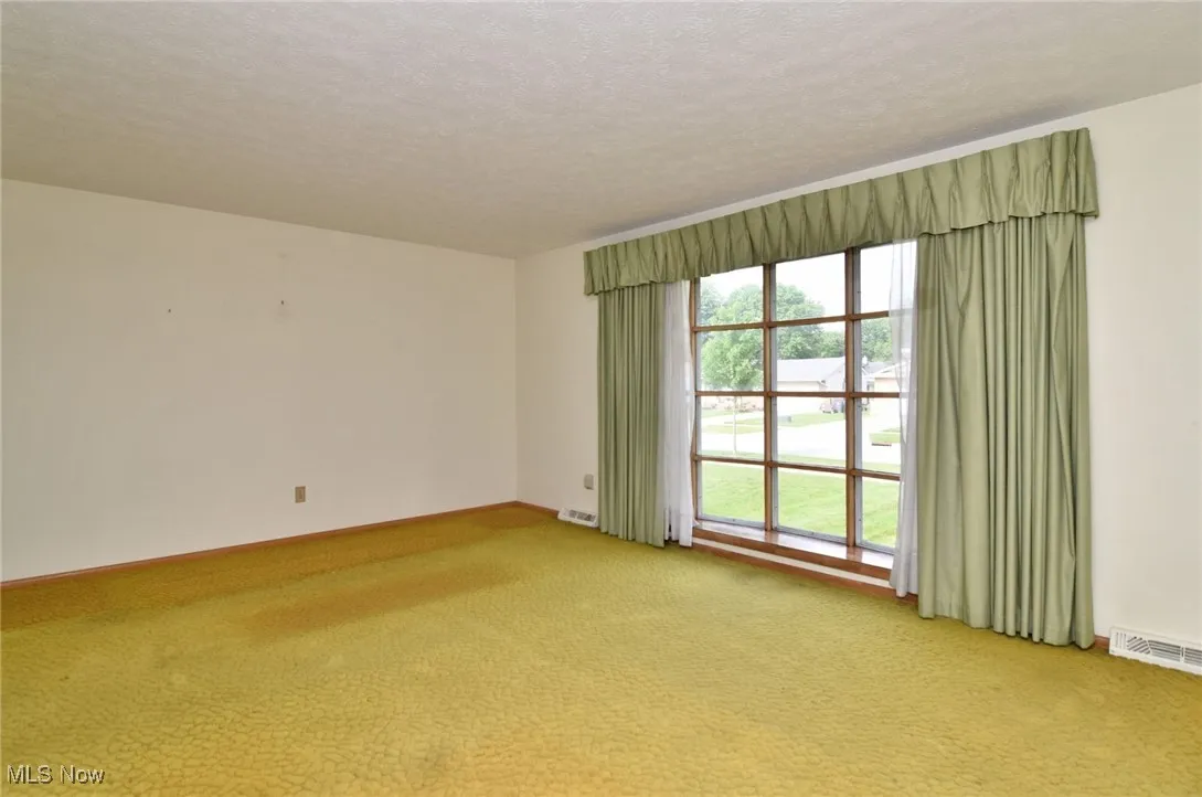 Unfurnished room with light carpet, baseboards, and a textured ceiling