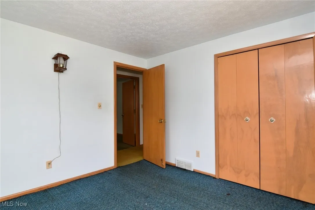 Unfurnished bedroom with carpet floors, baseboards, a textured ceiling, and a closet