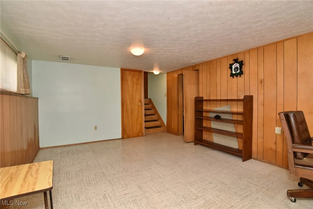Unfurnished office with wood walls, a textured ceiling, and baseboards