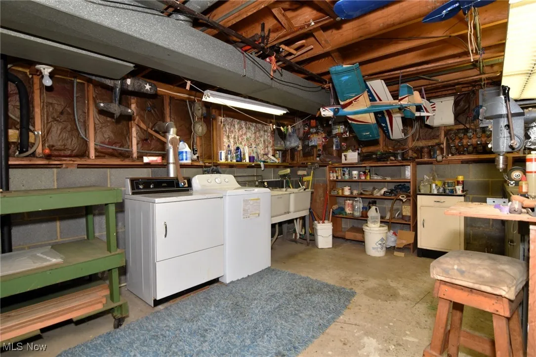 Unfinished below grade area with washing machine and clothes dryer and a workshop area