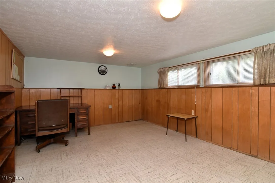 Office space featuring wooden walls, a textured ceiling, and a wainscoted wall