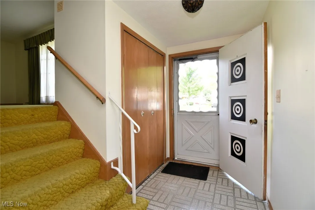 Foyer with brick patterned flooring, stairs, and baseboards