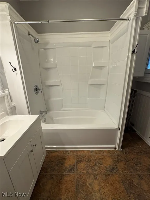 Full bath featuring bathing tub / shower combination, vanity, and stone finish flooring