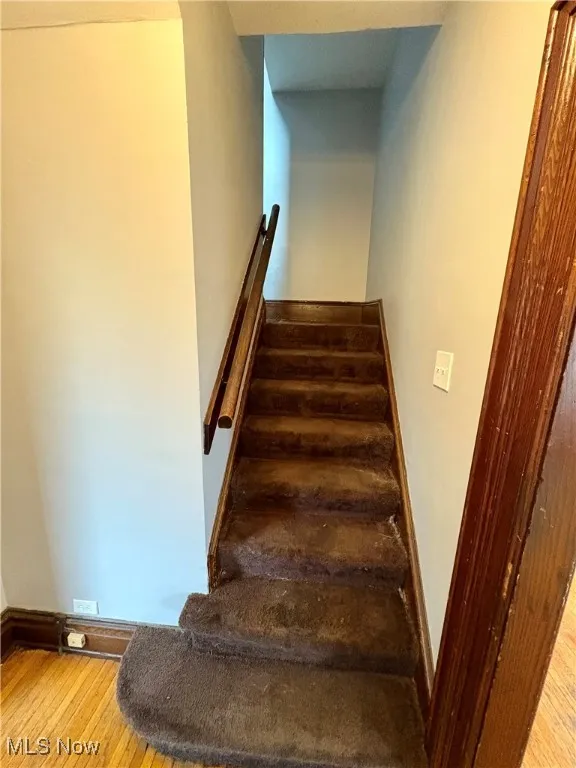 Stairway with wood finished floors and baseboards