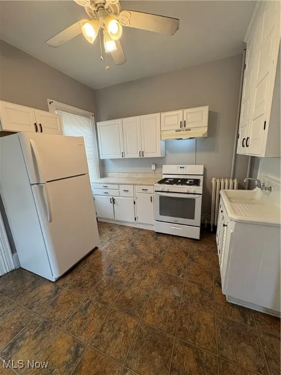 Kitchen featuring range, fridge, ventilation hood, radiator, and light countertops