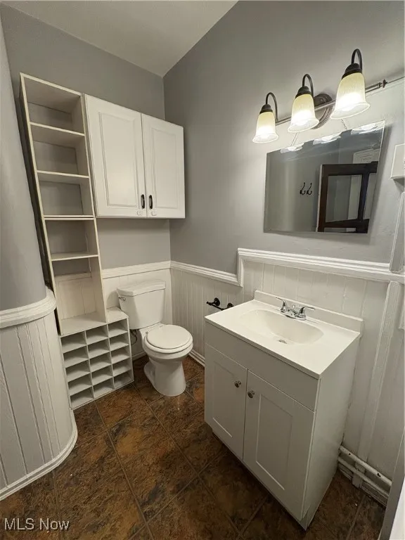 Bathroom with wainscoting, vanity, and toilet