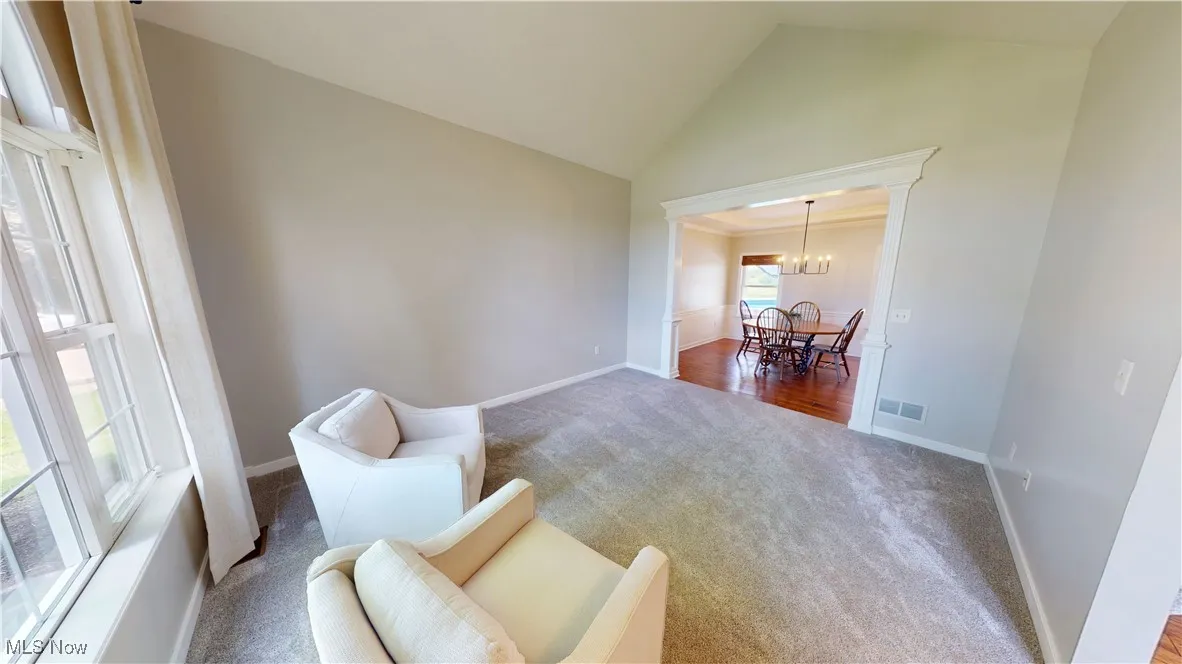 Sitting room featuring carpet floors, high vaulted ceiling, a chandelier, and baseboards