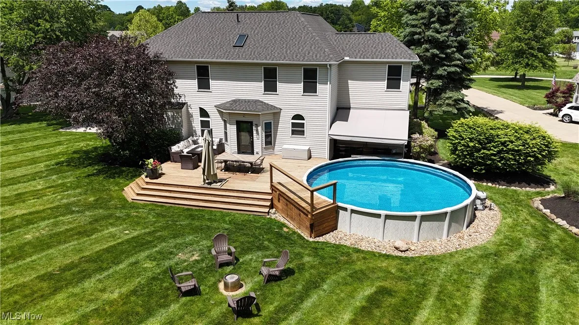 Rear view of house with a wooden deck, an outdoor pool, and a lawn
