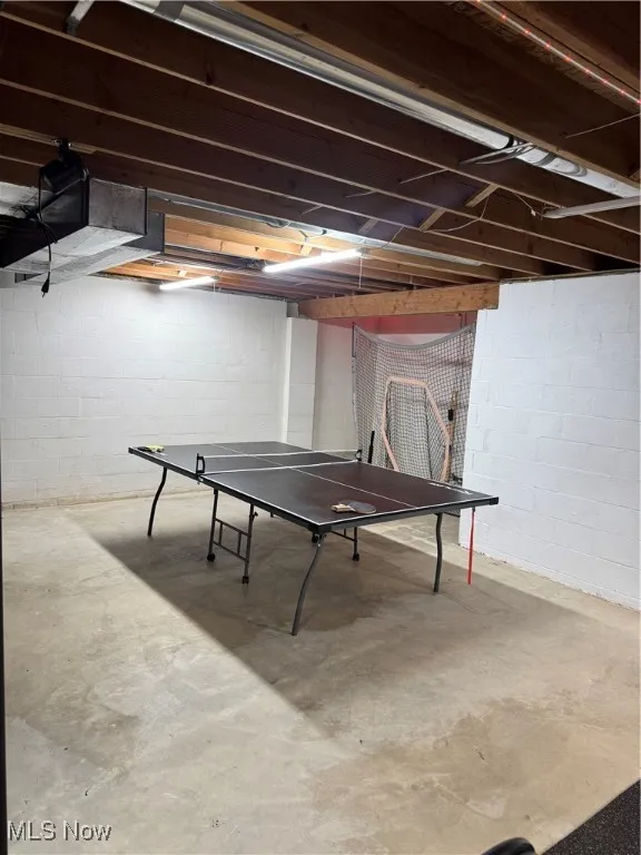 Rec room featuring unfinished concrete floors and concrete block wall