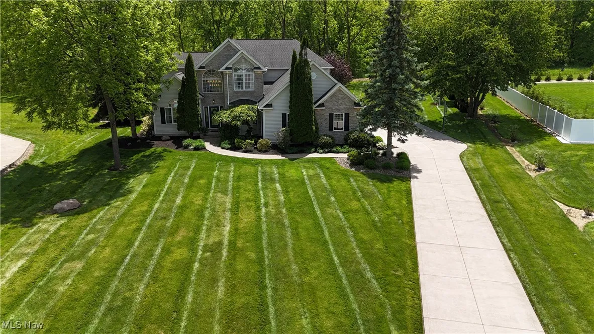 View of front of house with driveway and stone siding