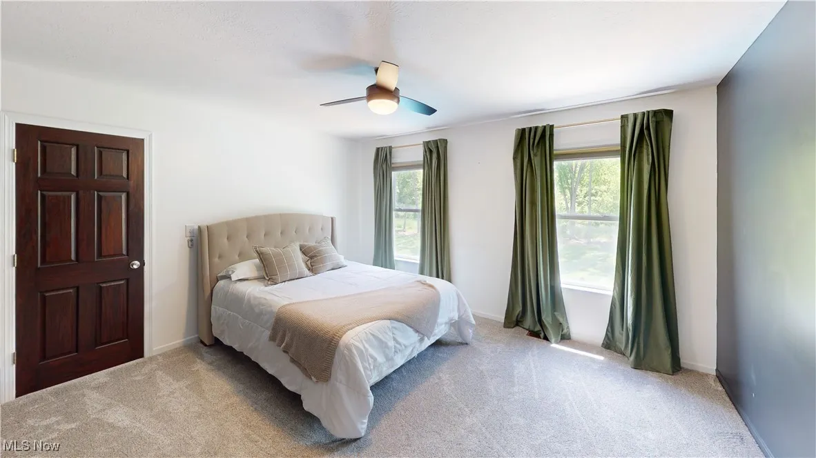Bedroom with light carpet, ceiling fan, and baseboards