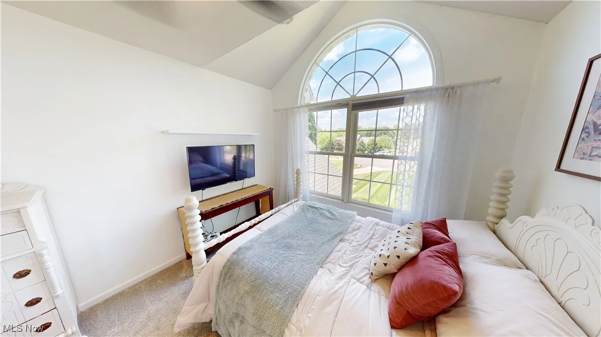 Carpeted bedroom featuring vaulted ceiling and baseboards