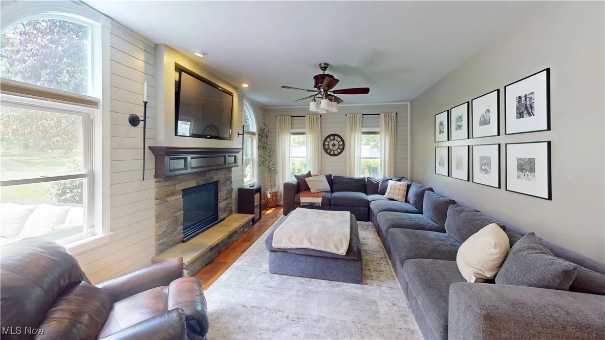 Living area with wood finished floors, a ceiling fan, a fireplace, and wood walls