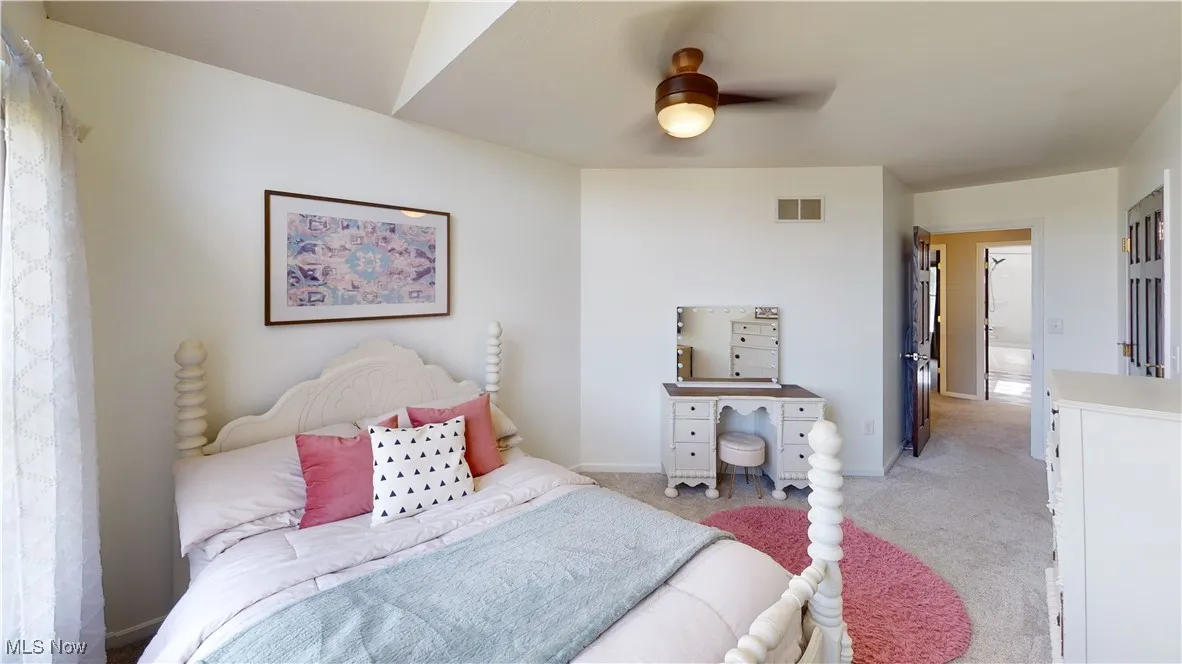 Bedroom with light carpet, a ceiling fan, and baseboards
