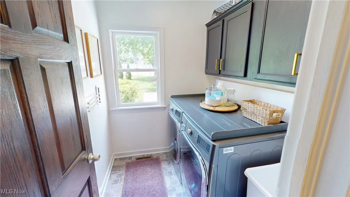 Laundry room featuring washer and dryer, cabinet space, and baseboards