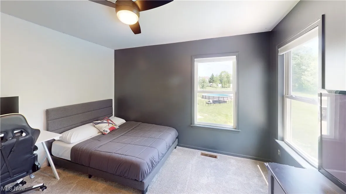 Bedroom featuring carpet, multiple windows, ceiling fan, and baseboards