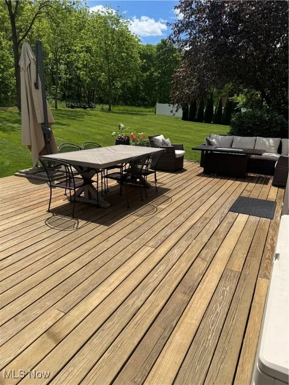 Deck with an outdoor hangout area, outdoor dining area, a yard, and view of wooded area