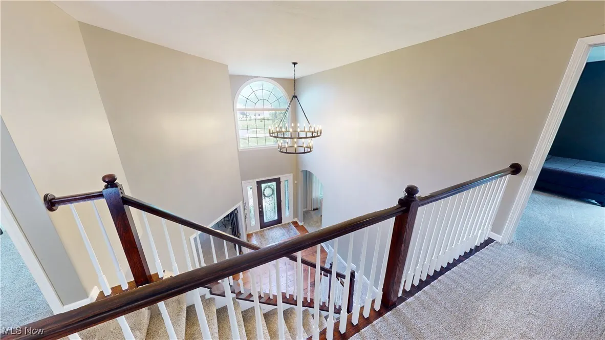 Stairway featuring carpet flooring, a chandelier, and baseboards