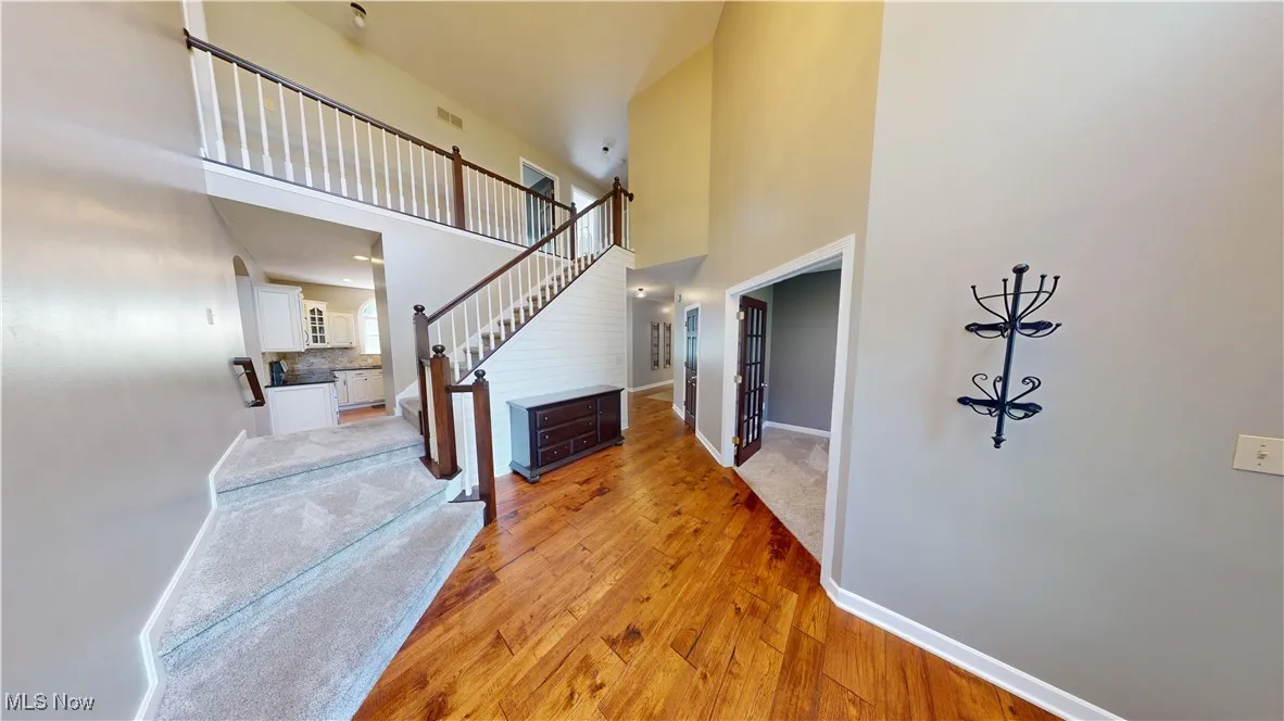 Foyer entrance featuring a high ceiling, stairs, light wood finished floors, and baseboards