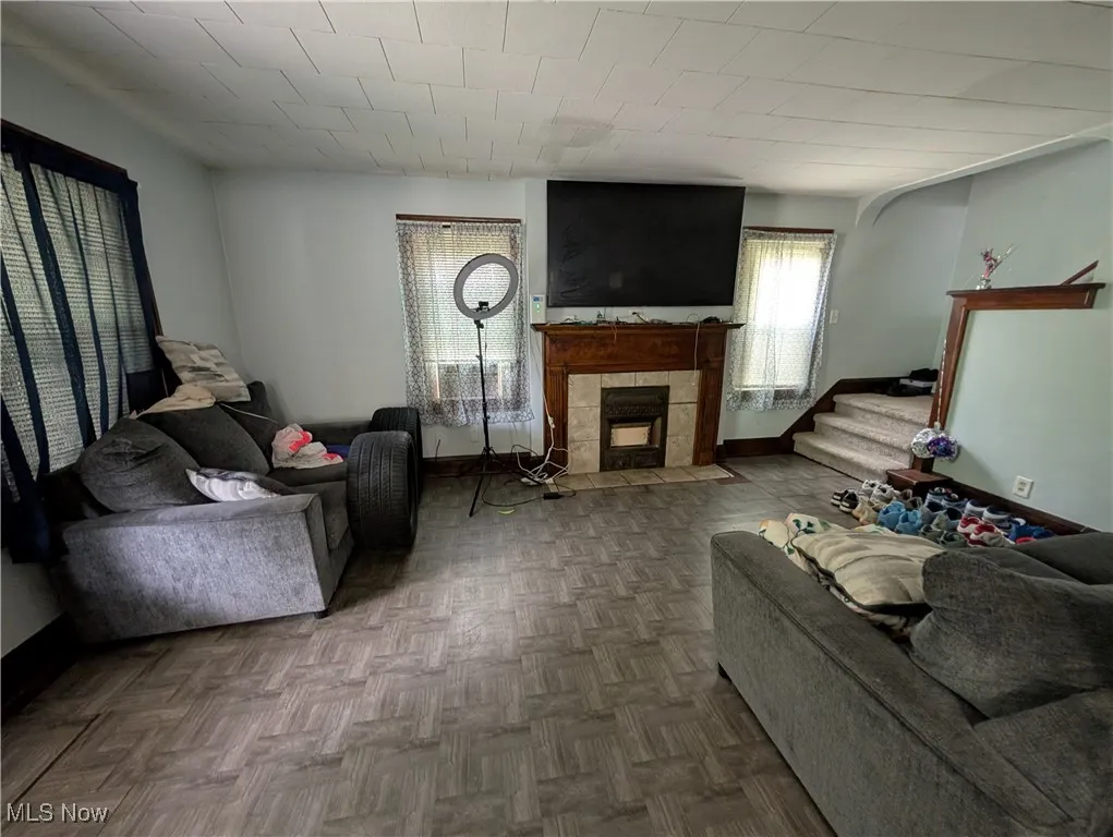 Living room with a tile fireplace, stairway, and baseboards