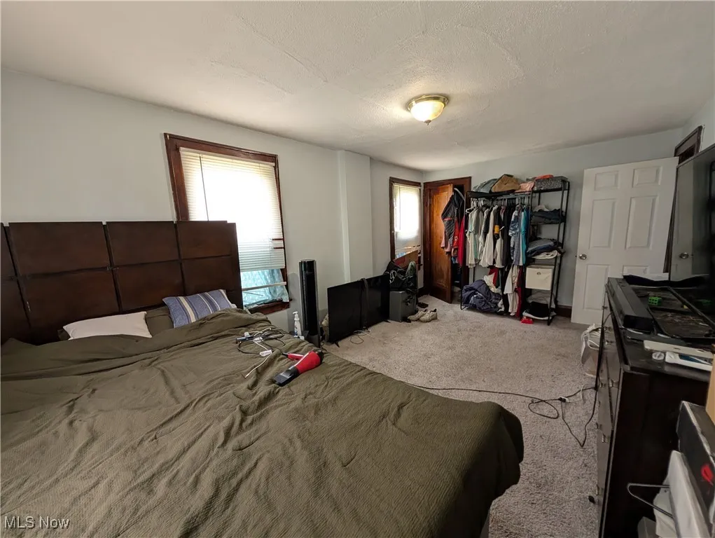 Carpeted bedroom with multiple windows, baseboards, and a textured ceiling