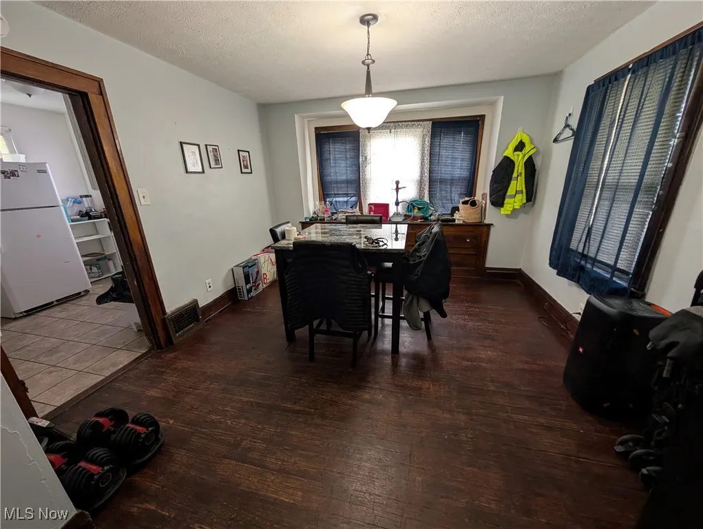 Dining area with a textured ceiling, wood finished floors, and baseboards