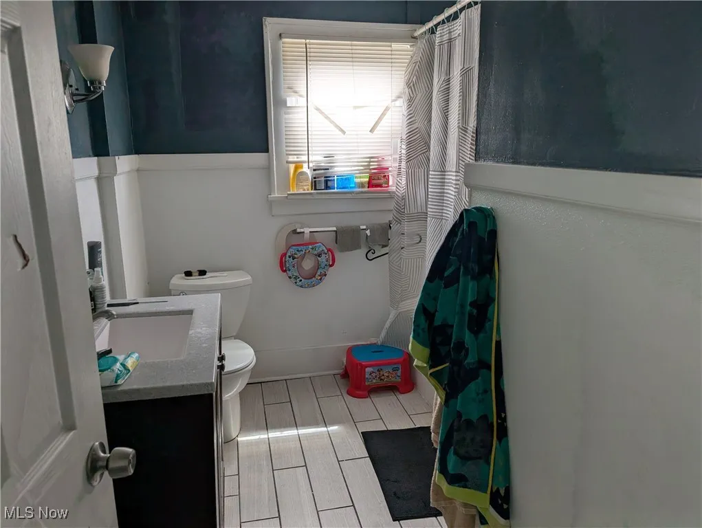 Bathroom featuring toilet, vanity, and a shower with shower curtain