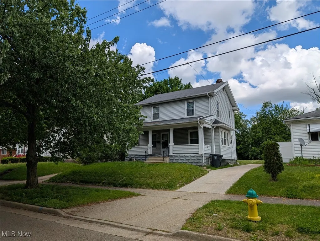 View of front of property featuring a porch, a front yard, and a chimney