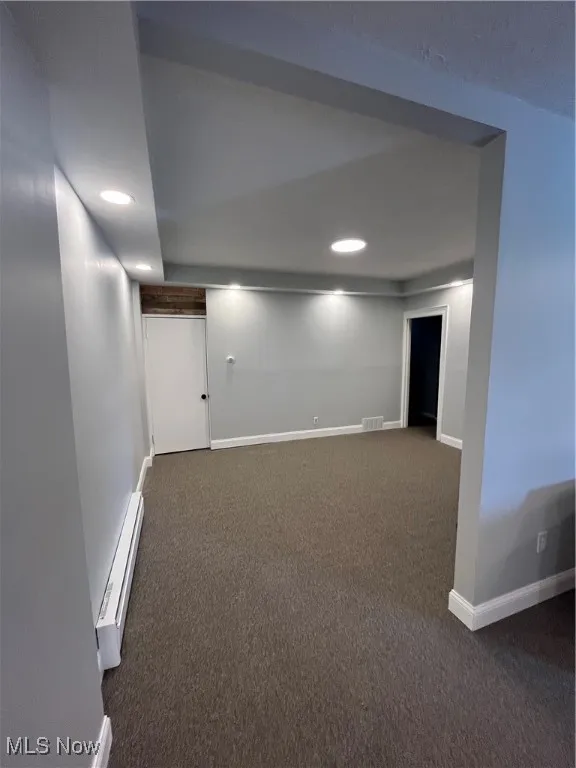 Finished basement with a baseboard heating unit, dark carpet, baseboards, and recessed lighting
