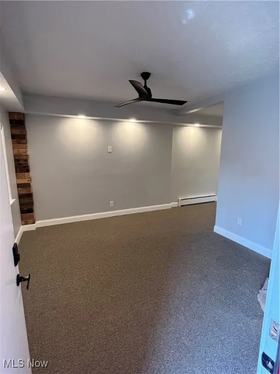 Unfurnished room featuring a baseboard radiator, ceiling fan, carpet flooring, and baseboards