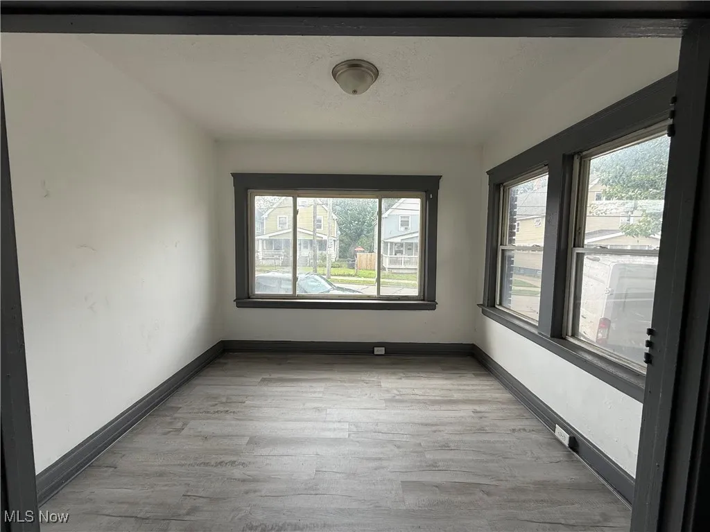 Unfurnished room with plenty of natural light, wood finished floors, and baseboards