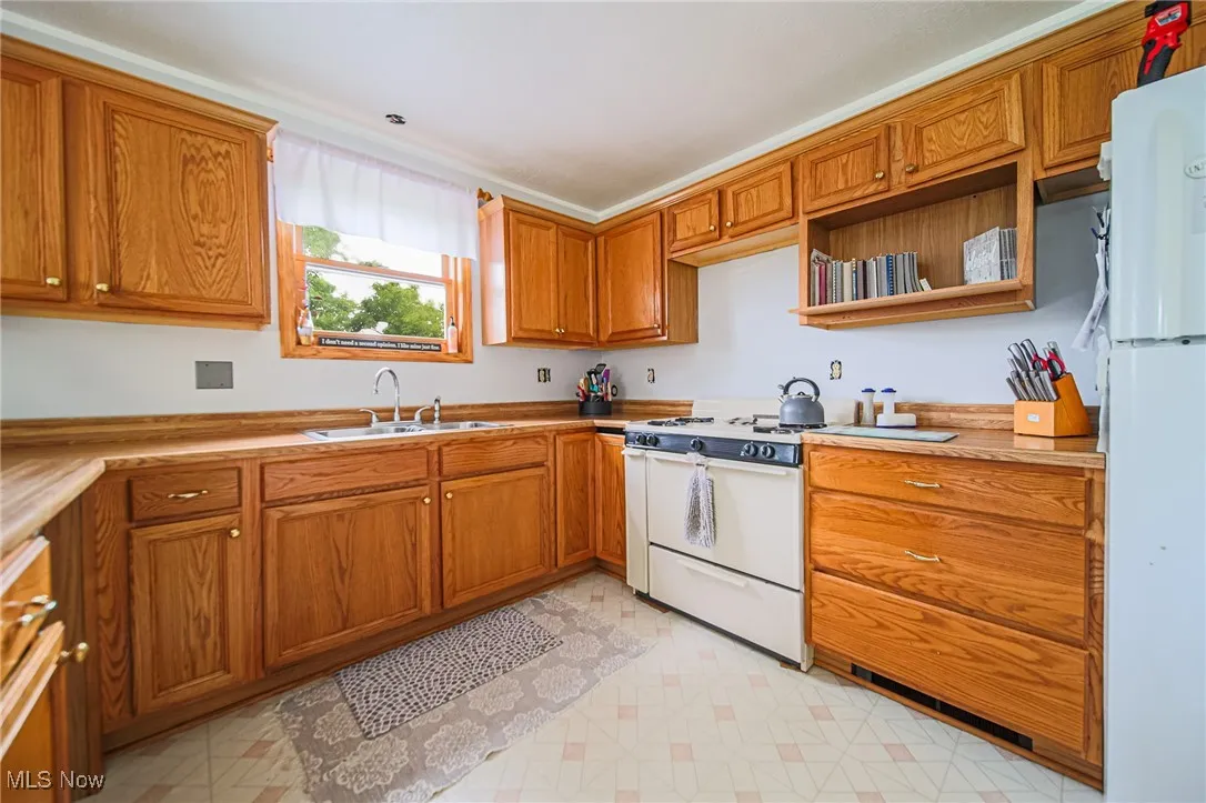 Kitchen featuring a sink, white appliances, and brown cabinetry