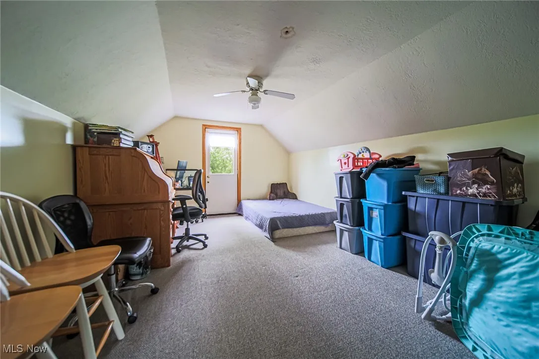 Carpeted bedroom featuring lofted ceiling, a textured ceiling, and ceiling fan