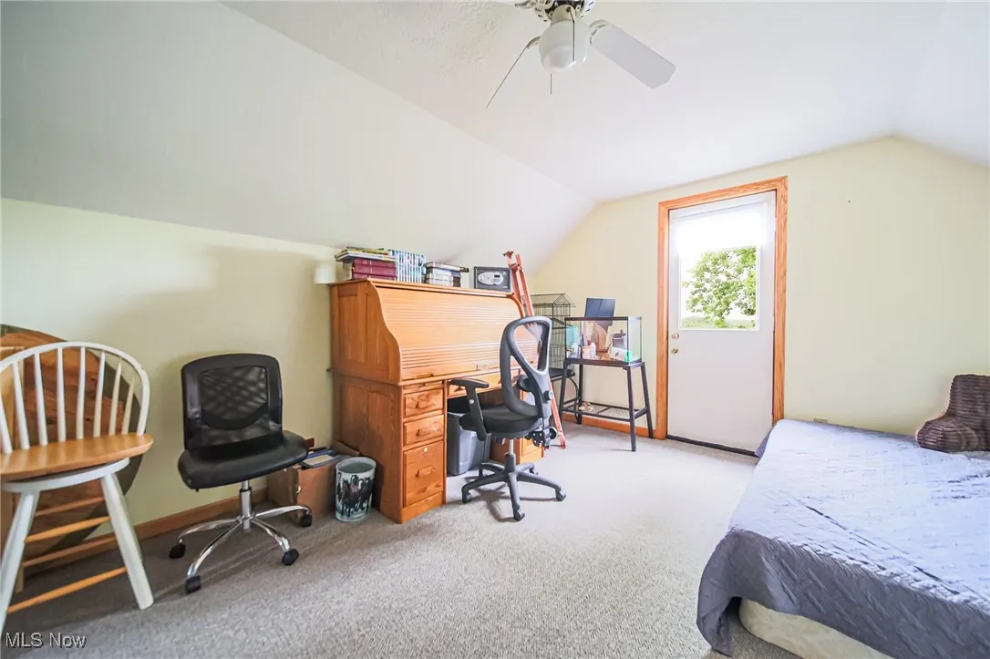 Bedroom with lofted ceiling, light carpet, and a ceiling fan