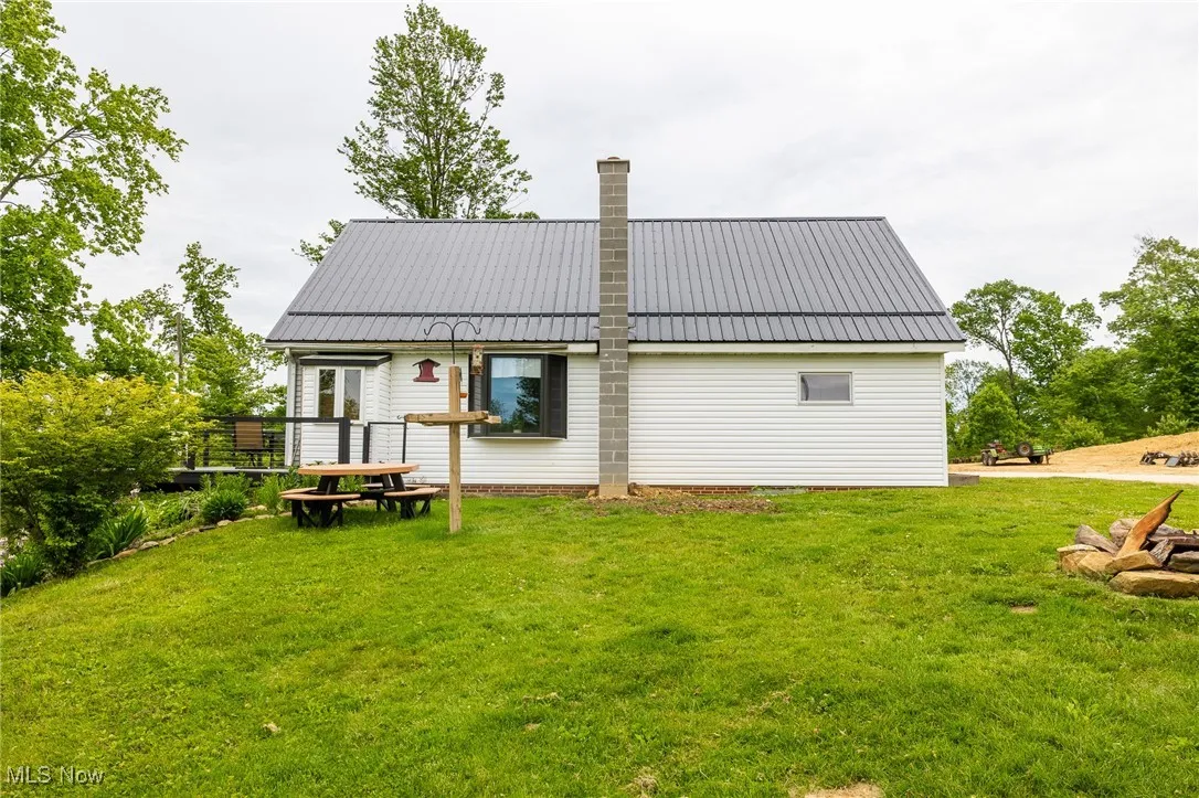 Back of house with a chimney, a yard, and metal roof