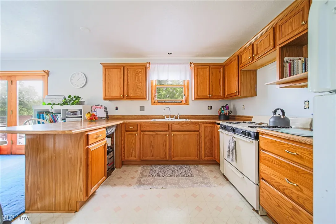 Kitchen with white appliances, a sink, a peninsula, and plenty of natural light