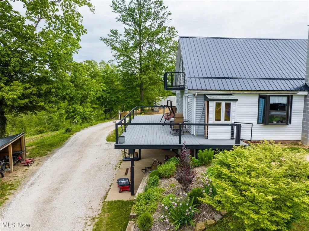 Rear view of house with a deck, driveway, and metal roof