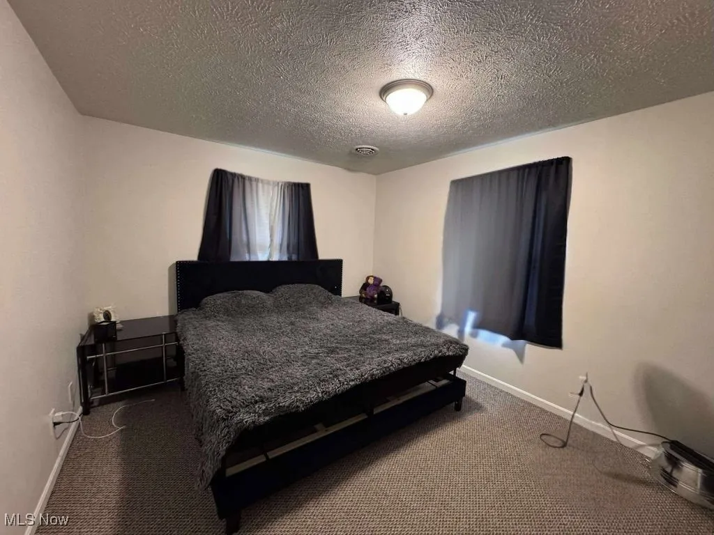 Carpeted bedroom with baseboards and a textured ceiling