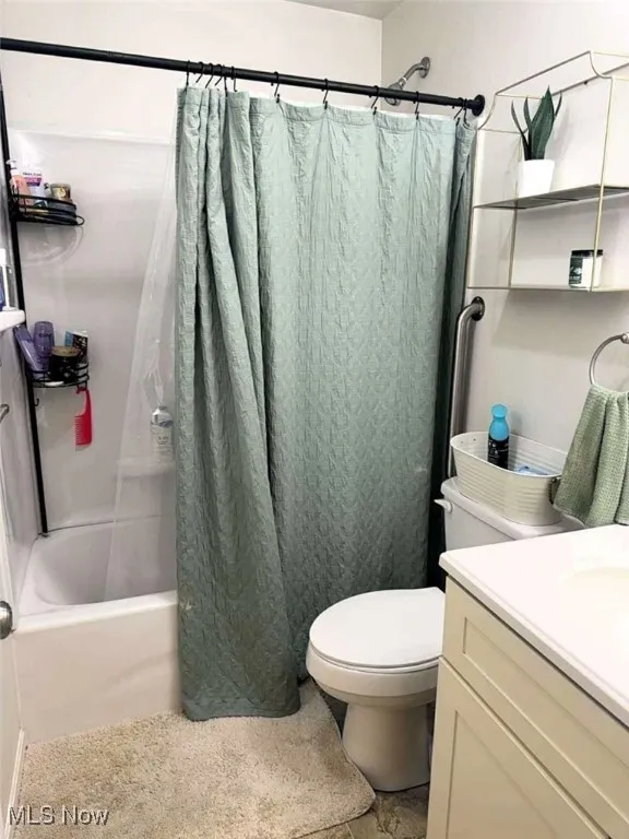 Bathroom featuring shower / bathtub combination with curtain, vanity, and toilet