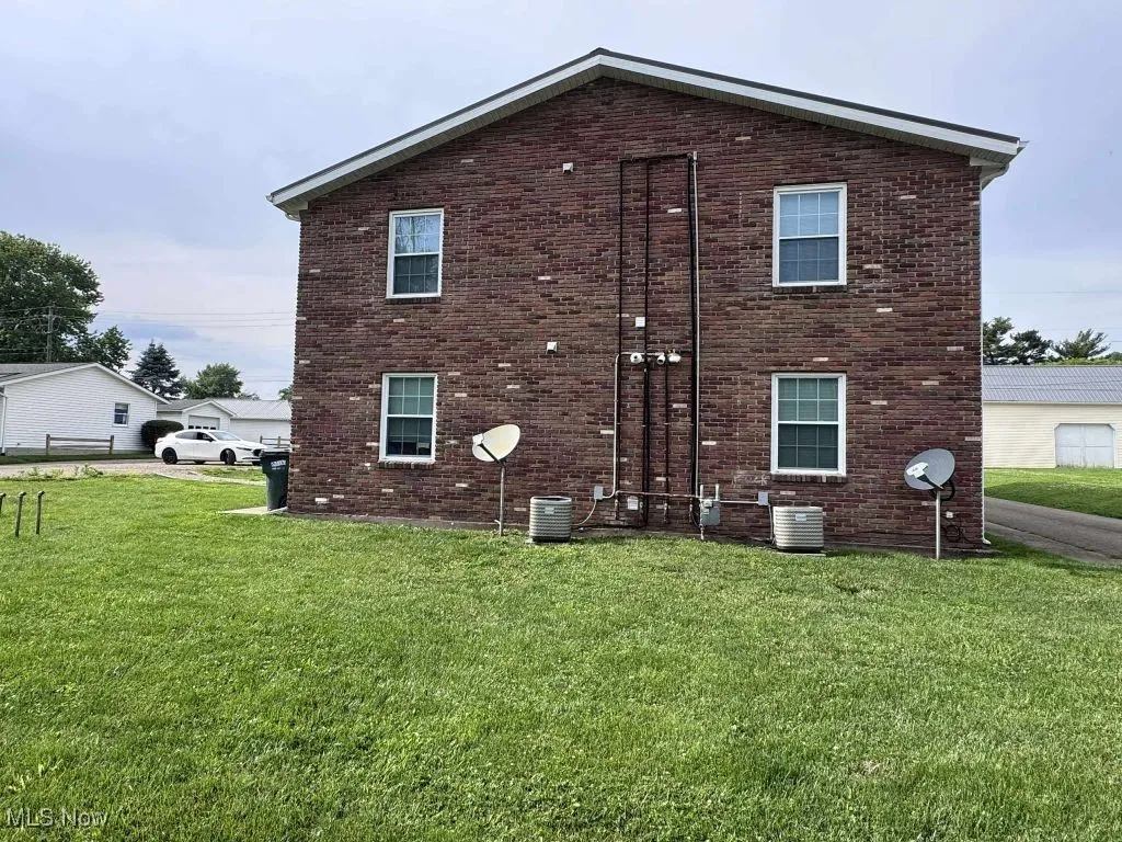 View of home's exterior featuring brick siding, a lawn, and central air condition unit