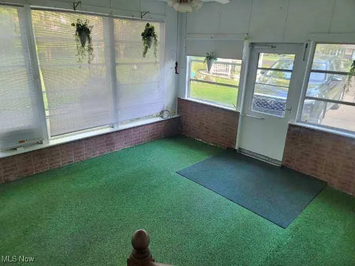 Unfurnished sunroom featuring carpet flooring and a ceiling fan