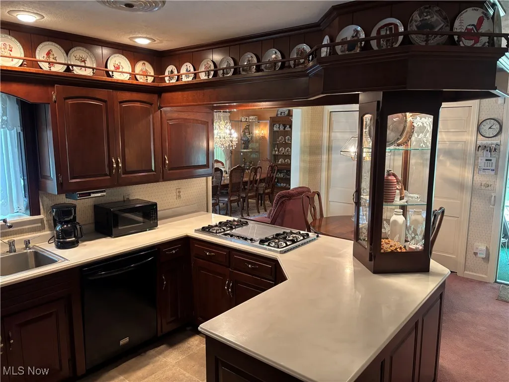 Kitchen with black appliances, a sink, light countertops, and a peninsula
