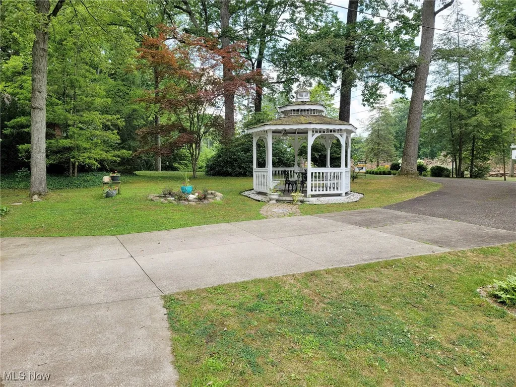 View of grassy yard featuring a gazebo and driveway