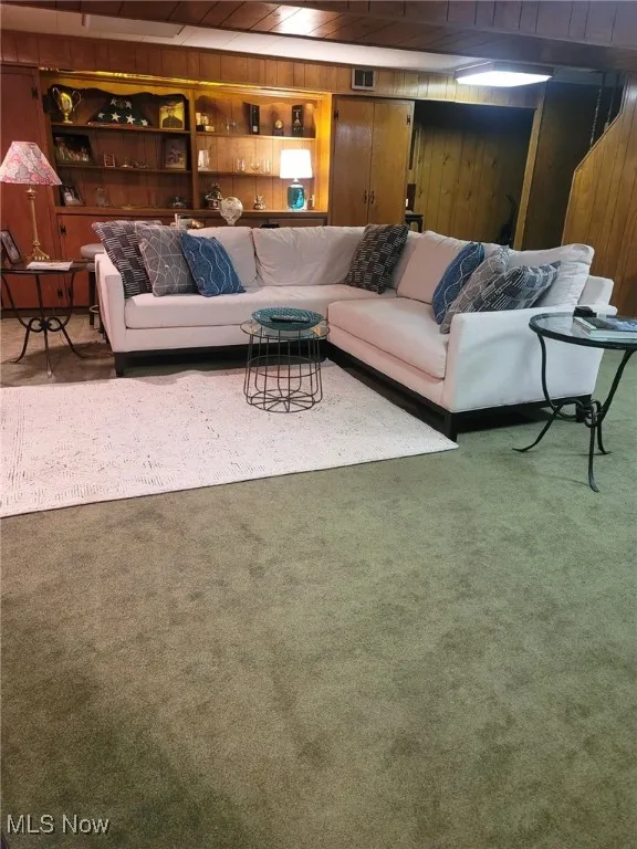 Carpeted living area featuring wood walls