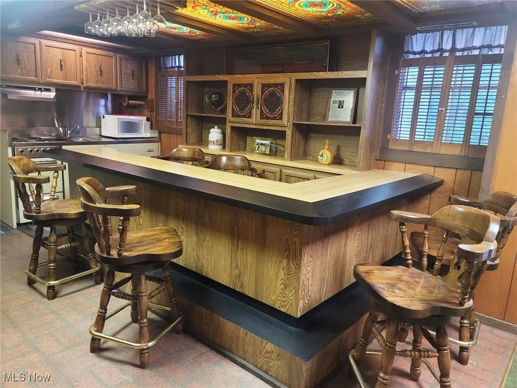 Indoor bar featuring white microwave and under cabinet range hood