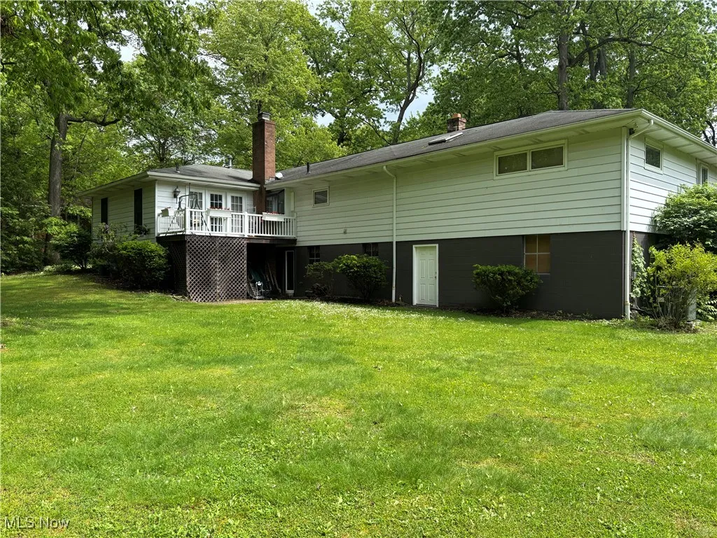 Back of house featuring a deck, a yard, and a chimney